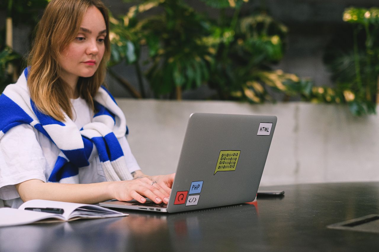 Services Young woman with a laptop working in a modern indoor space, showcasing freelance and digital nomad lifestyle.
