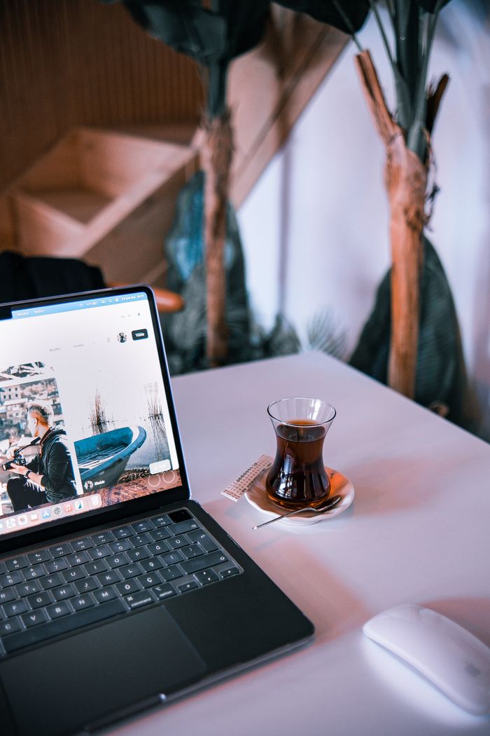 Services A laptop and traditional tea on a table in a modern indoor setting.